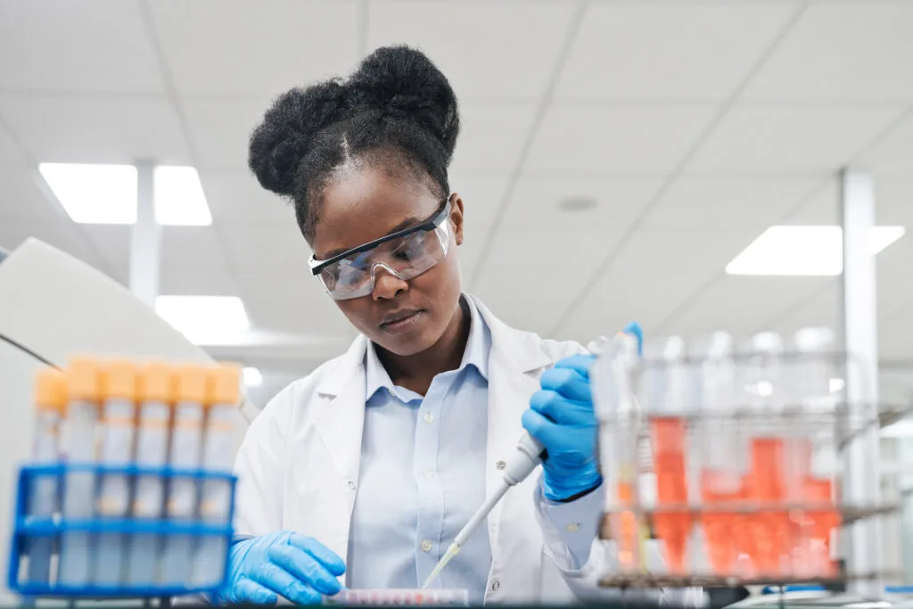 A woman wearing a white coat uses laboratory tools